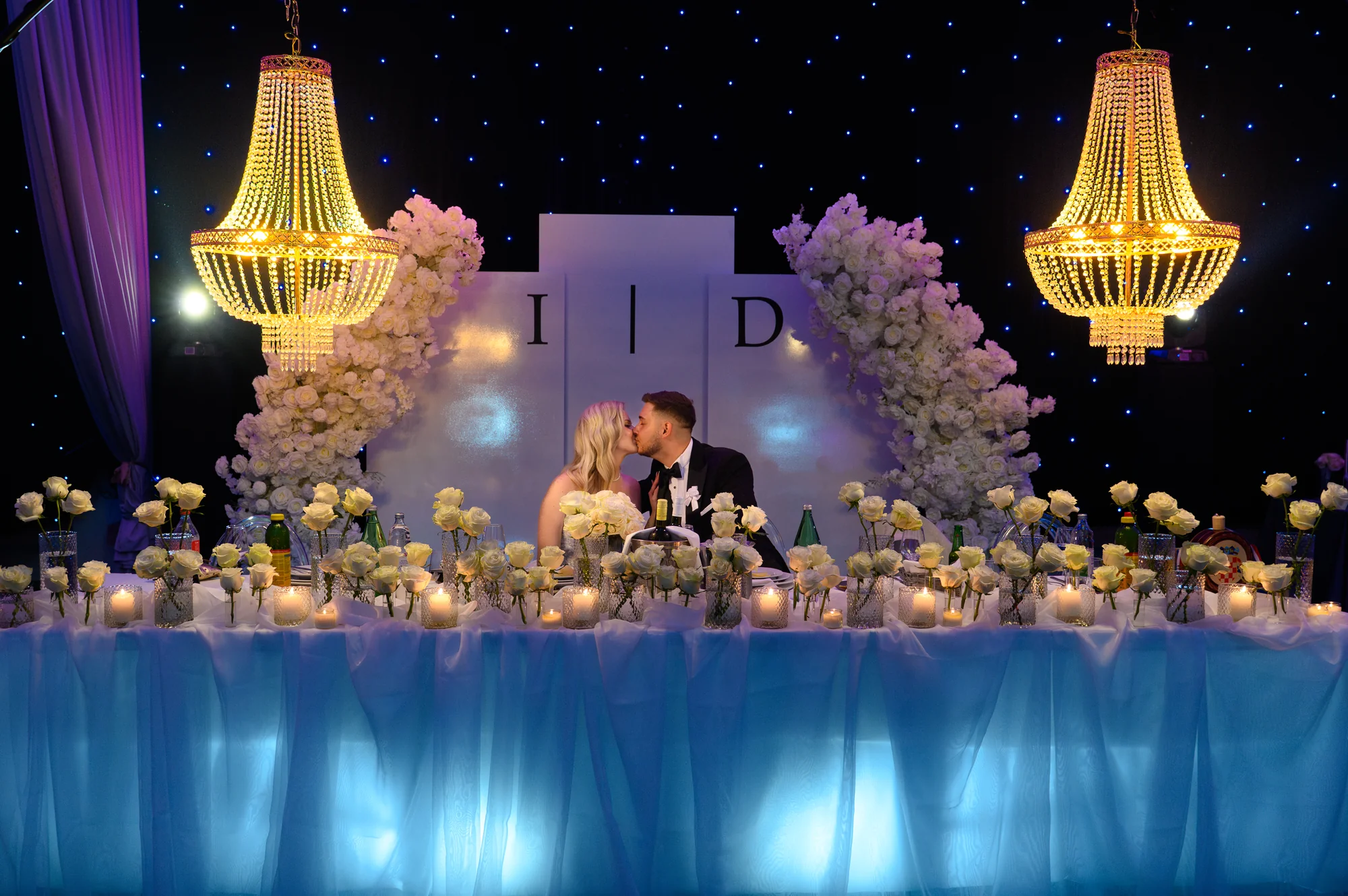 Mladenci se ljube za svečanim stolom — MI Weddings.